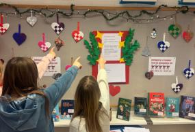 Tre elever peger på dagens opslag på PLC-opslagstavlen Tre elever peger på dagens opslag på PLC-opslagstavlen